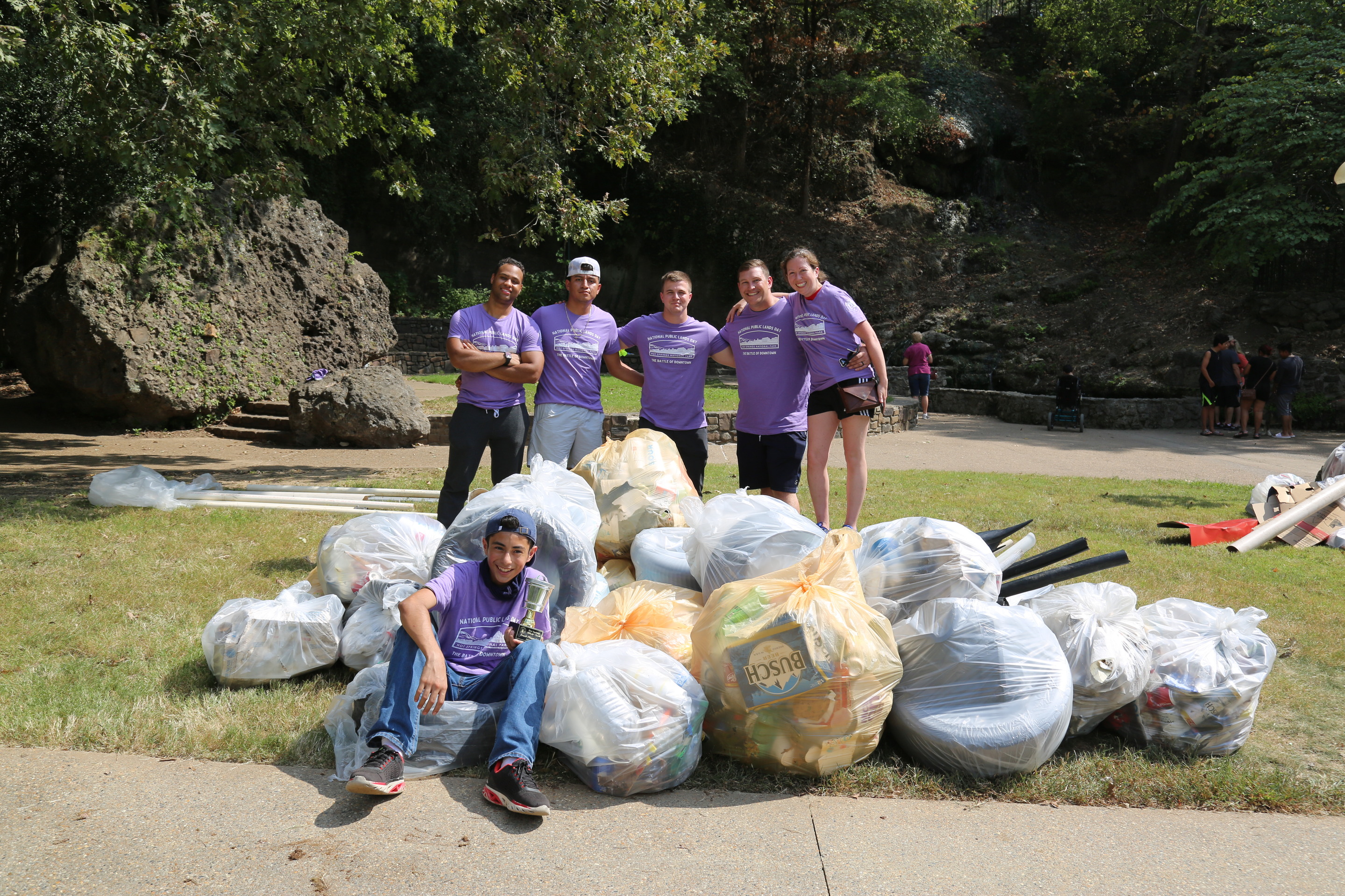 A group of volunteers proudly displays their winning trophy during a trash collection competition during National Public Lands Day. 