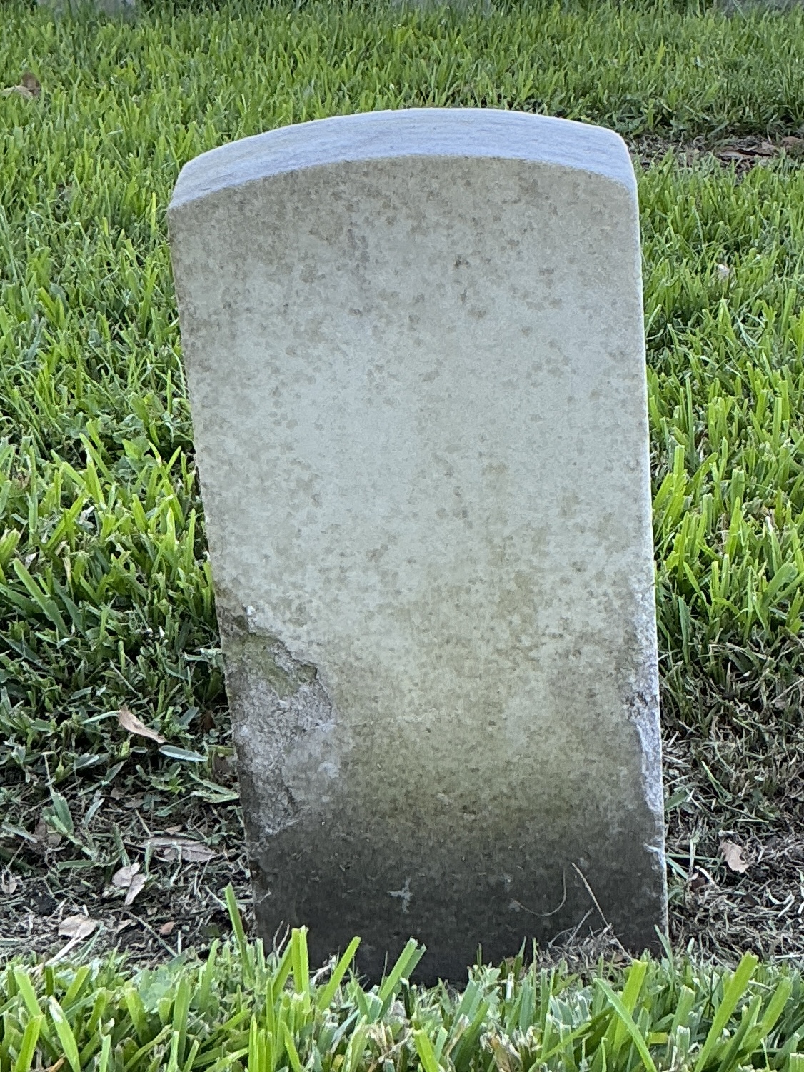 Back of historic upright marble headstone with recessed shield face.