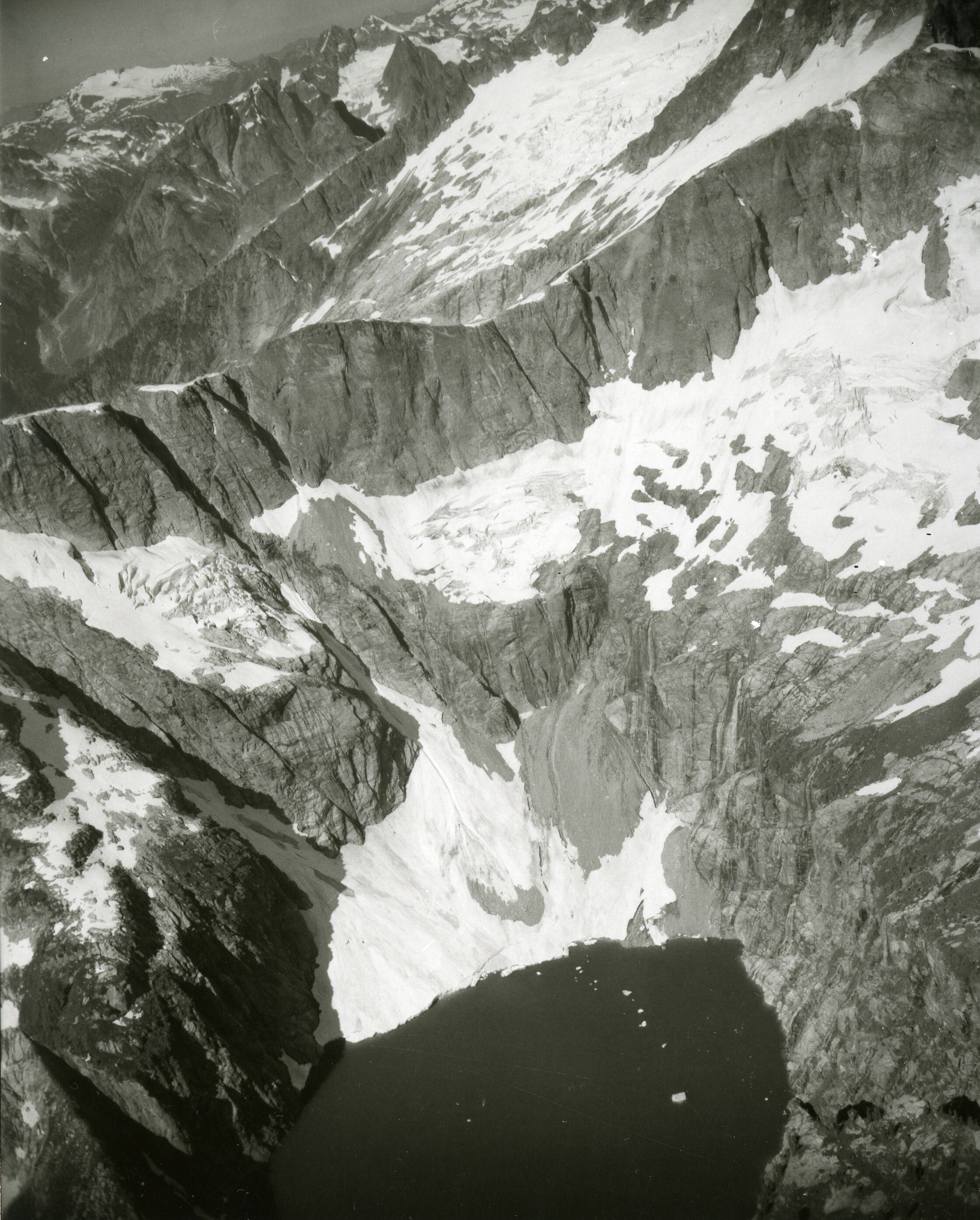 A mountain lake below rocky mountaintop and glacier.
