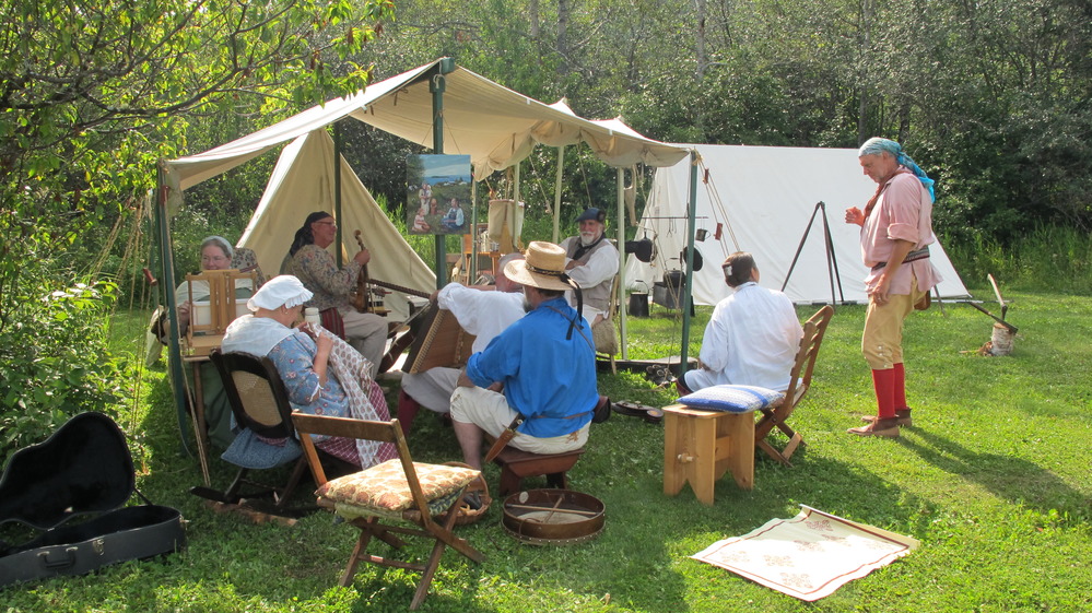 Reenactors in historic dress socialize in the historic encampment.
