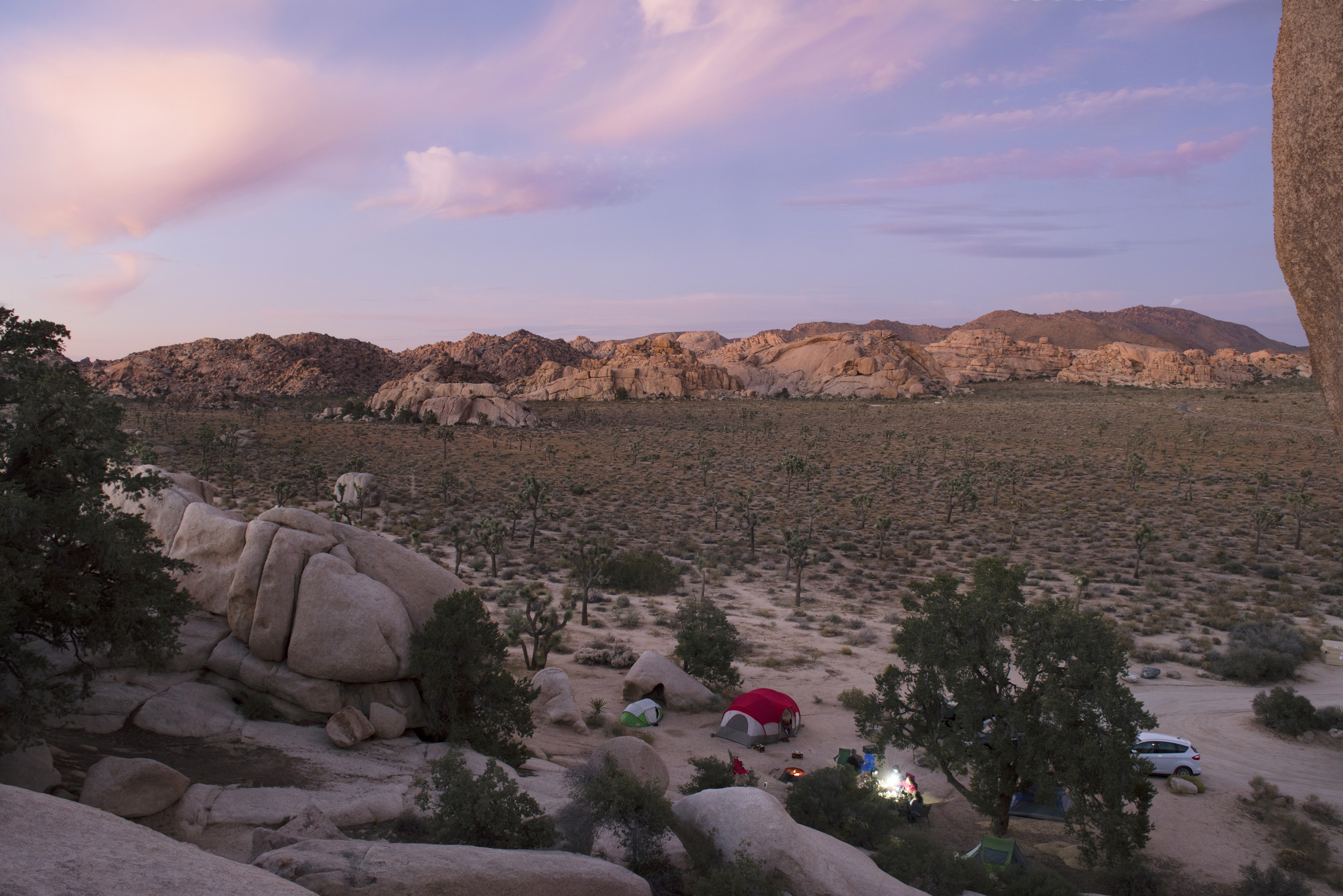 A small campsite with two tents and people at a picnic table. 