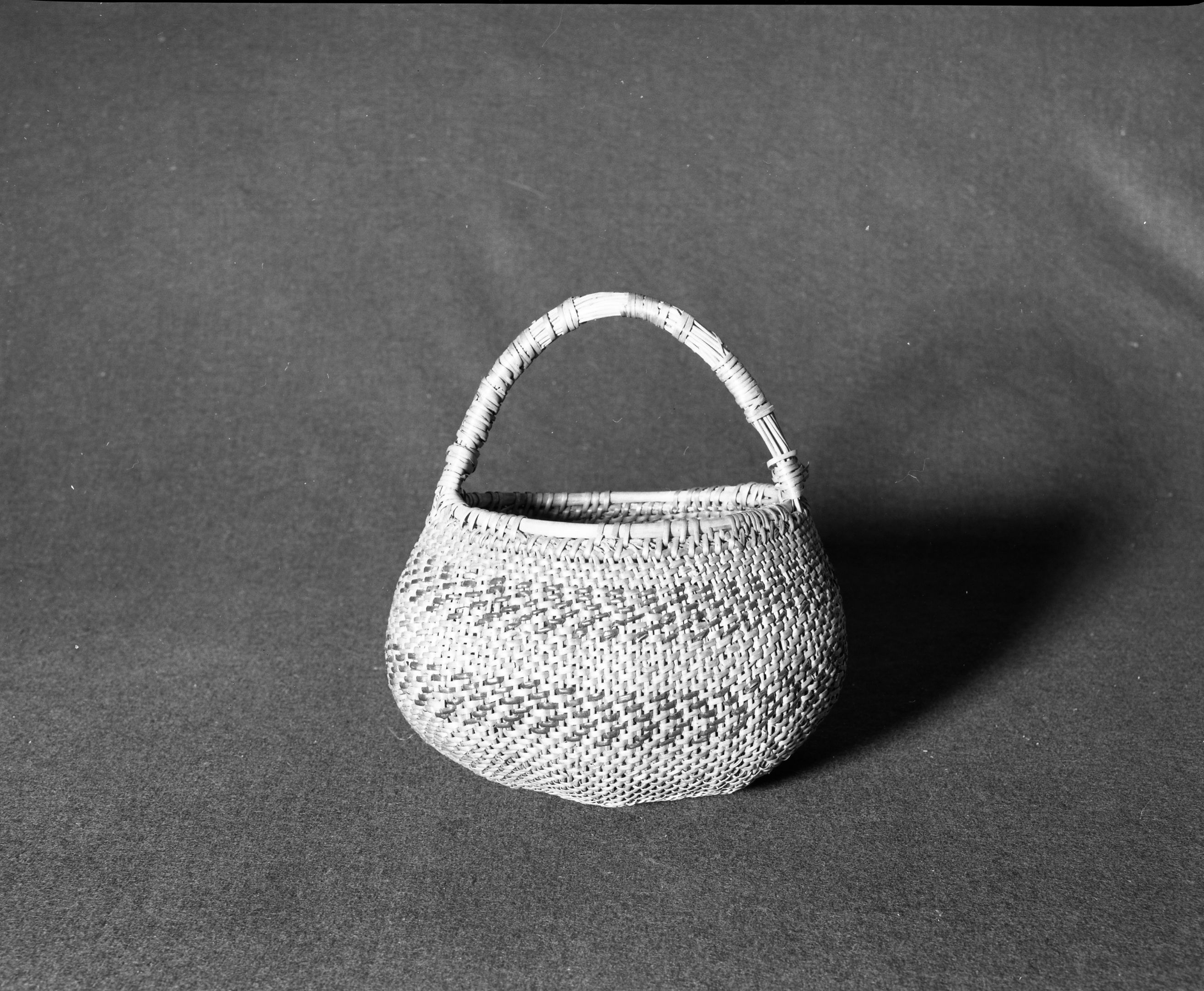 Marie Rozier Collection, Catalog No. 53. Object: Miwok handled basket. Dimensions: 9 x 6 x 9". Materials: Split redbud, scraped shoots, split bull pine (?). Technology: Diagonally twined, up to the right slant of turns. Collection History: Bought in Carters, Tuolumne by Miss Annie Teague in 1905. Photographed by Michael Dixon in December 1982. Catalogued by Craig Bates and Barbara Beroza. Yosemite Collections, National Park Service.