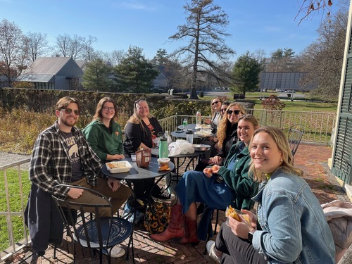 People gather outside eating lunch near a garden. 