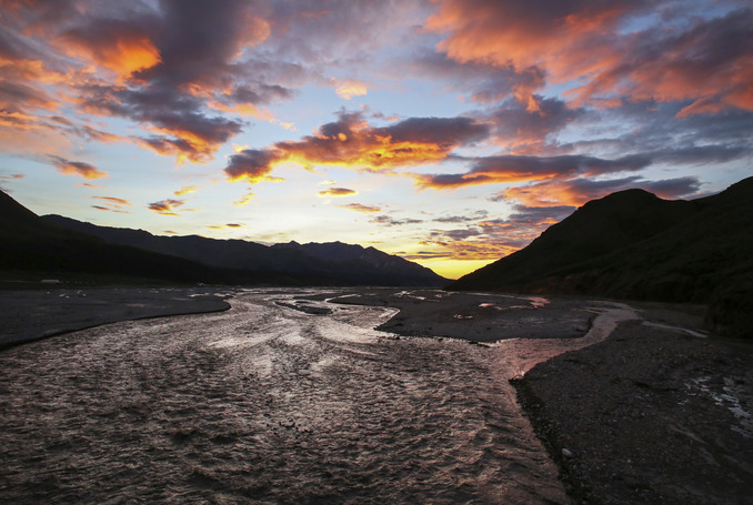 sky of pink clouds over dark mountains and a large river
