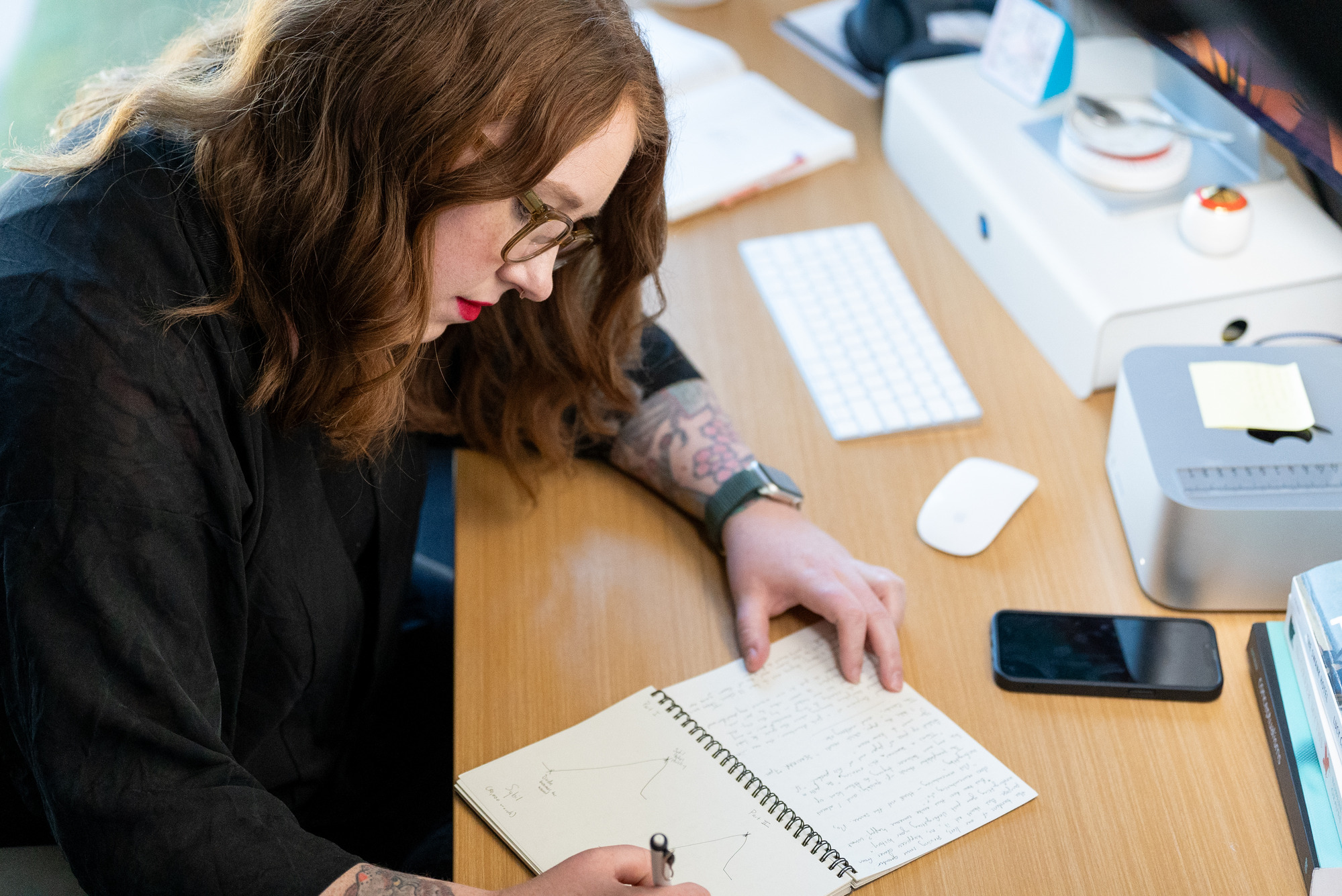 A writer sits at her desk and writes in a notebook 