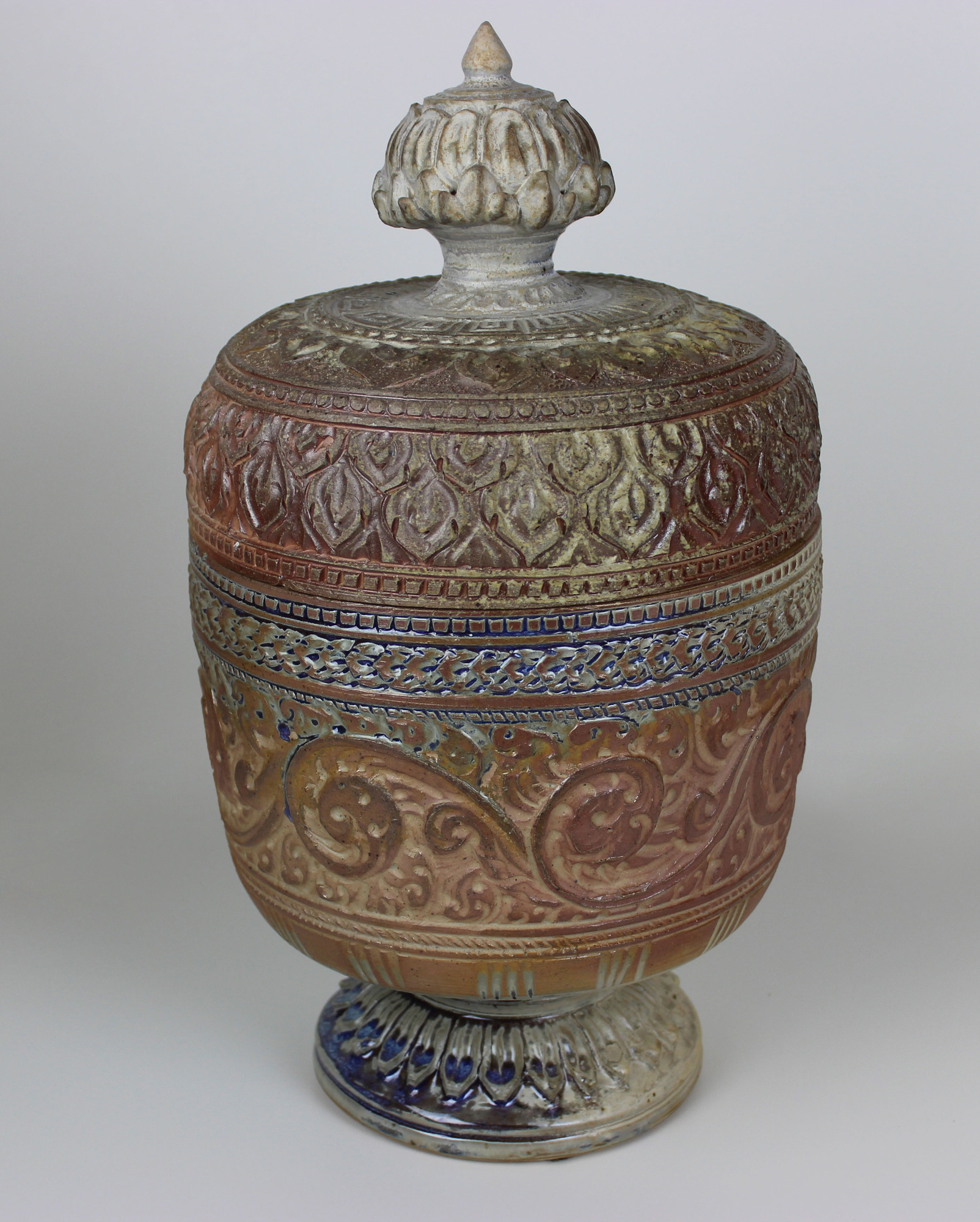 The jar has a rounded foot and low waist, with an ovoid body. The main motif on the jar are foliate swirls. Above this, there is a rope-like band, then a bead-like band. Then a pattern of boomerang-like shapes. 