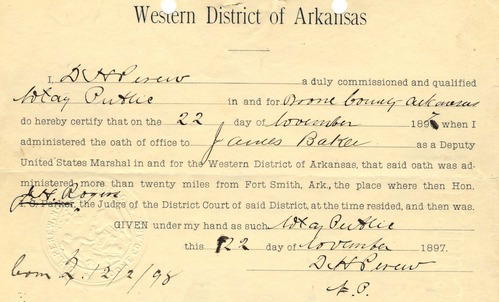 An aged slip of paper titled, "Western District of Arkansas," dated November 22nd, 1897. Text reads: I, a duly commissioned and xx in and for Boone County, Arkansas, do hereby certify that on the 22 day of November 1897 when I administered the oath of office to James Baker as a Deputy United States Marshal in and for the Western District of Arkansas, that said oath was administered more than twenty miles from Fort Smith, Ark., the place where then Hon. J. H. Rogers, the Judge of the District Court of said District, at the time resided, and then was.