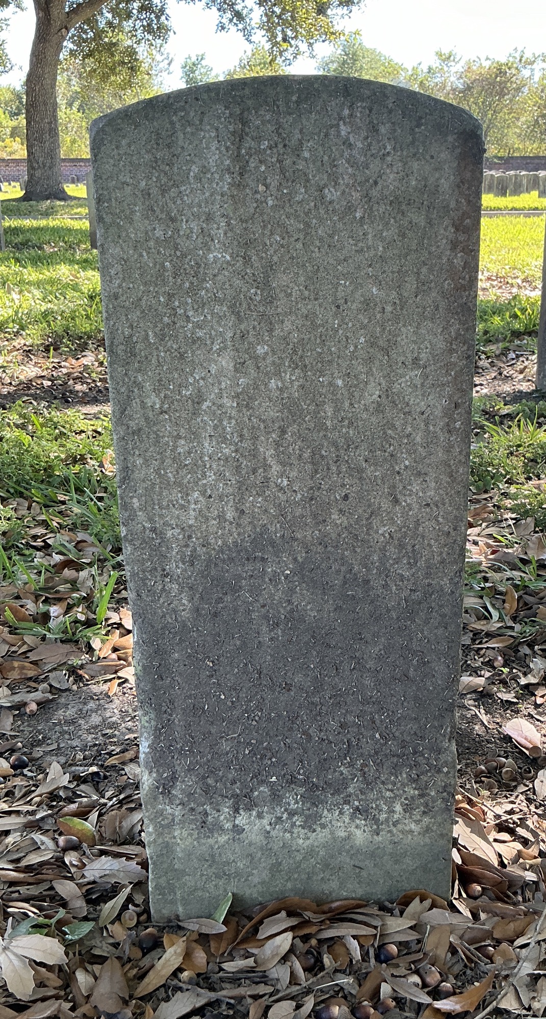 Back of historic upright marble headstone with recessed shield face.