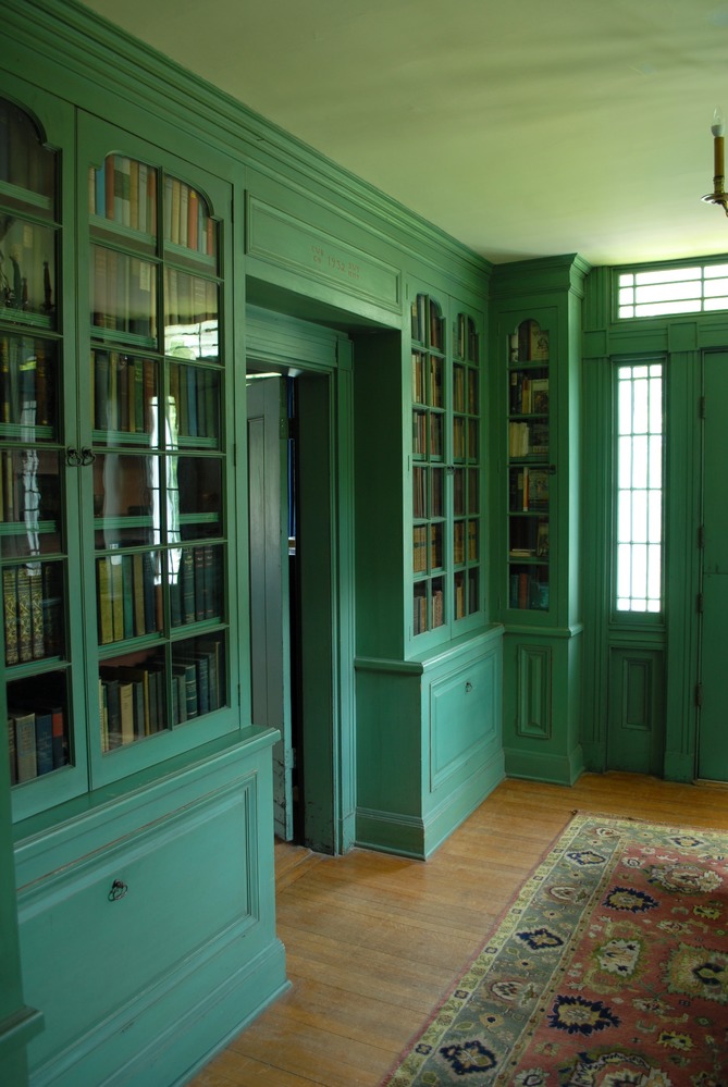 Two wooden green bookcases filled with books.