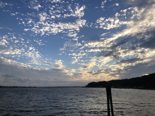 river with choppy water and small clouds scattered across the sky