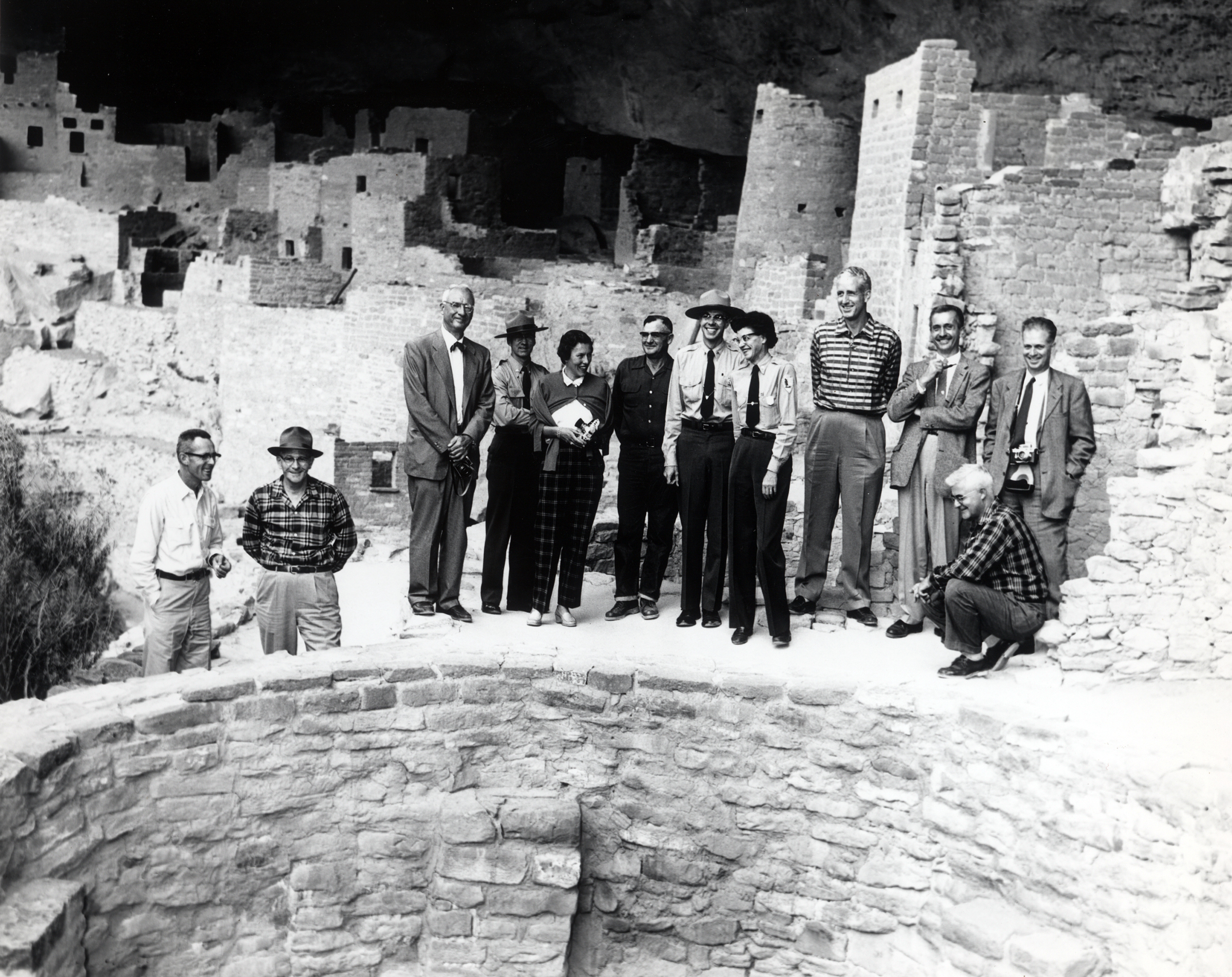 Jean Pinkley, wearing her NPS uniform, and two other rangers address a group standing around a circular structure.
