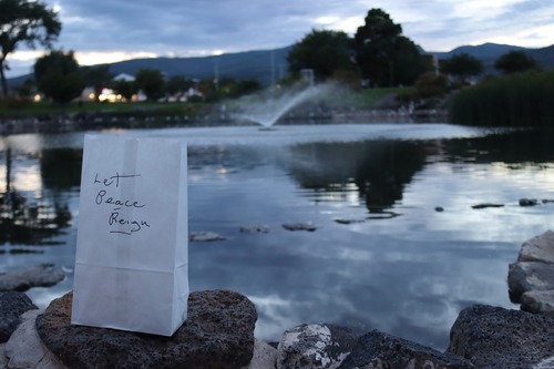 A white bag on a rock with the message "Let Peace Reign." Behind it is a pond with a fountain.