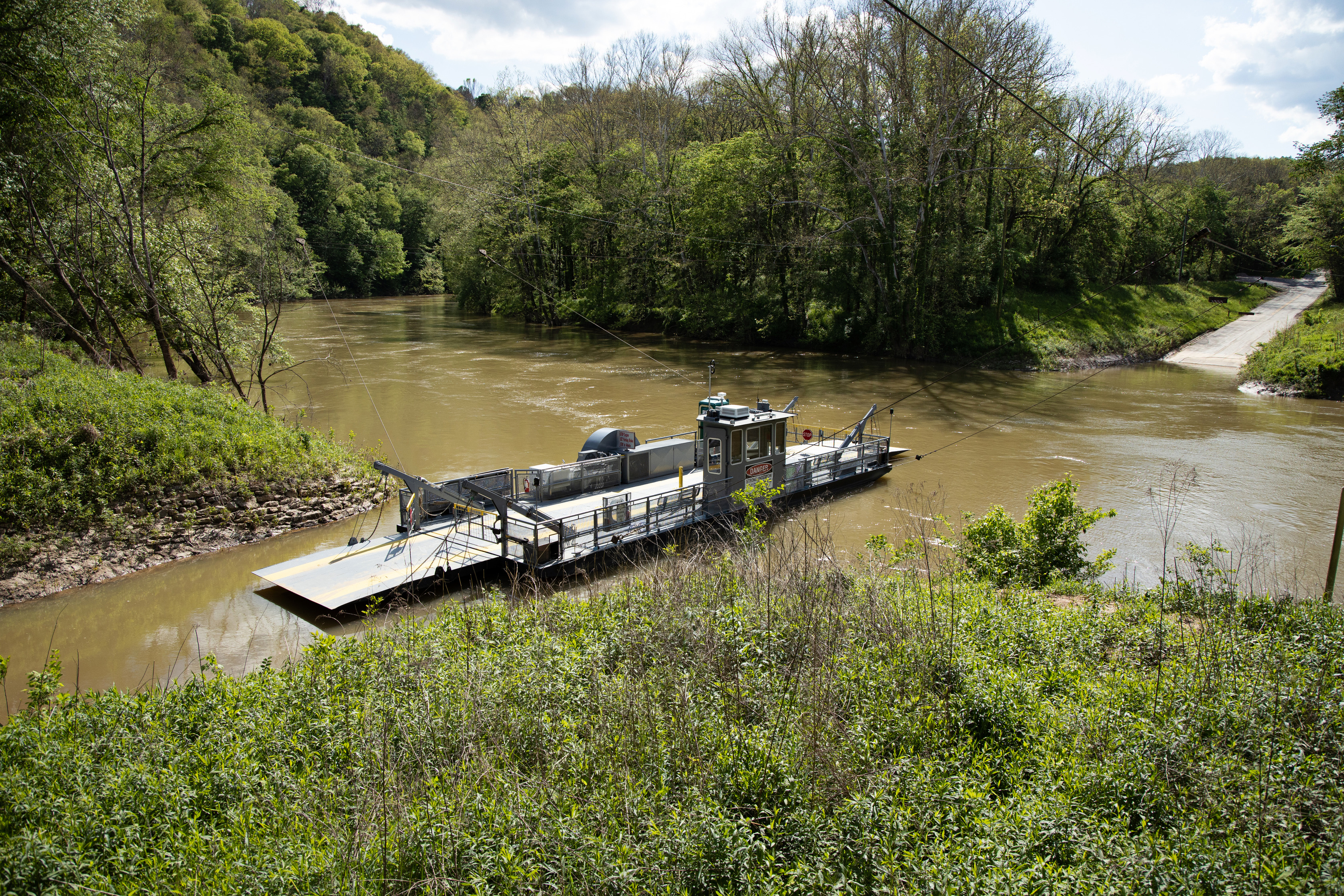 A river ferry floats on top of brown river water. 