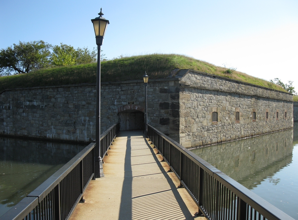 A boardwalk leading over a moat to a stone fort.