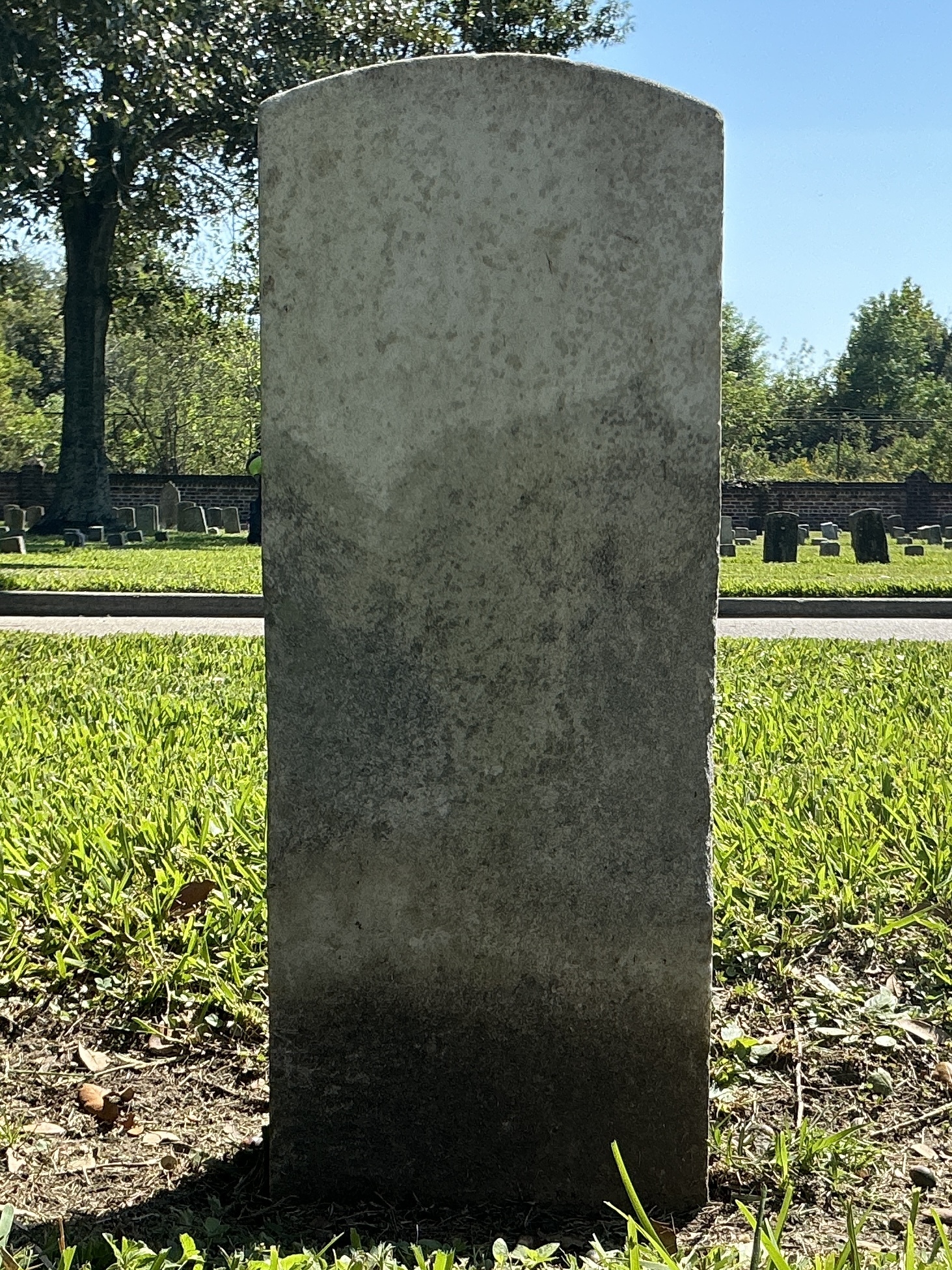 Back of historic upright marble headstone with recessed shield face.