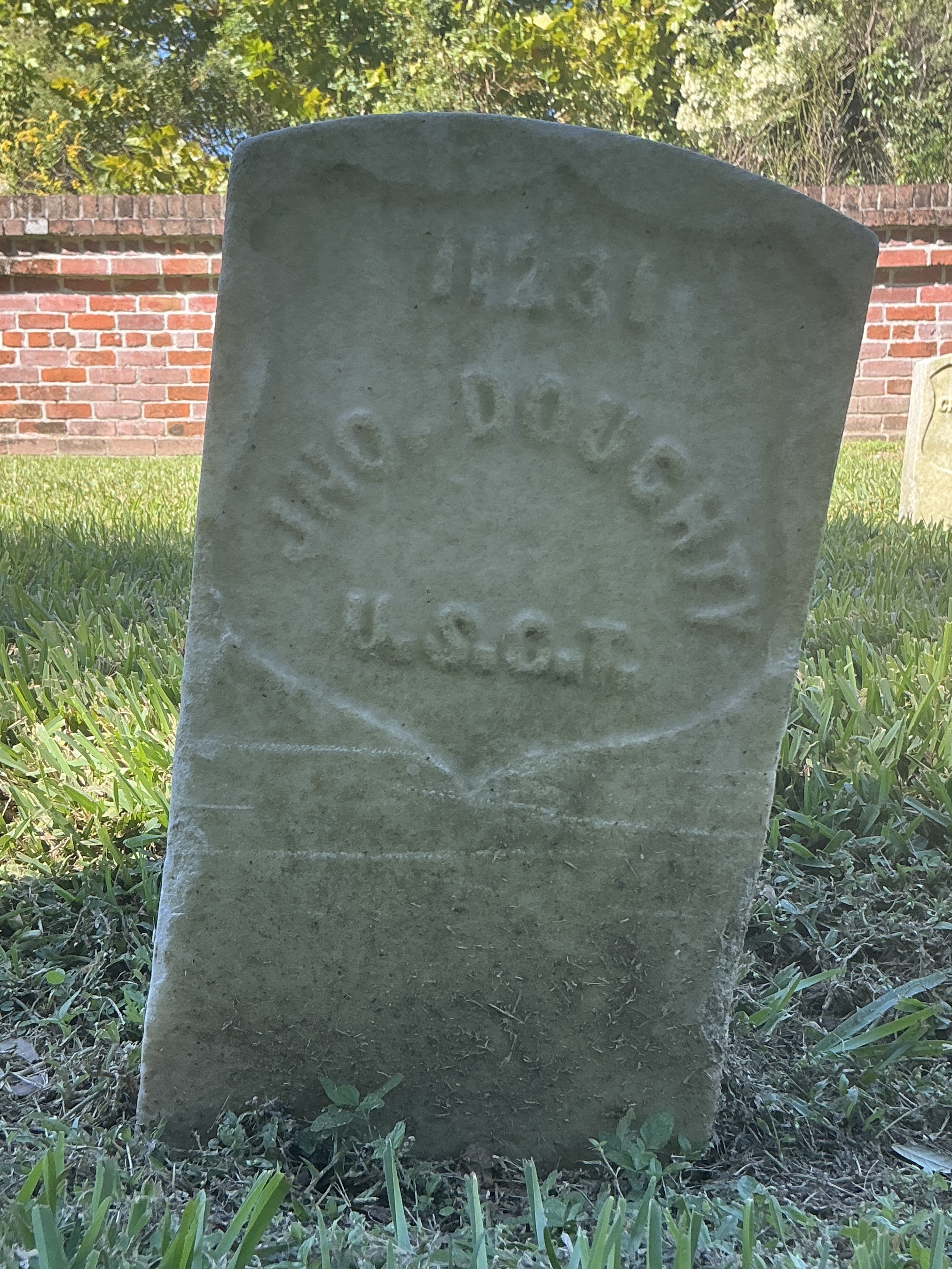 Front of historic upright marble headstone with recessed shield face.