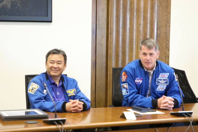 Two astronauts sitting at a table.