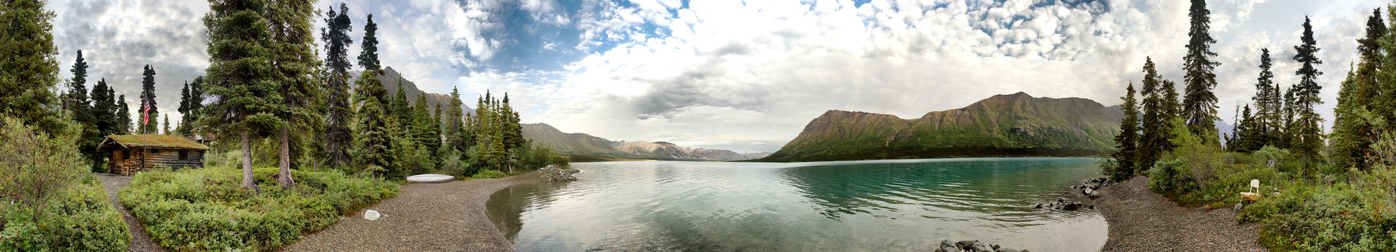 A wooden cabin on the shore of blue lake.