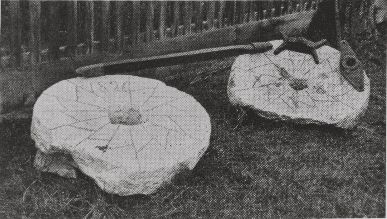 Black and white image of two round and worn stones alongside assorted metal pieces