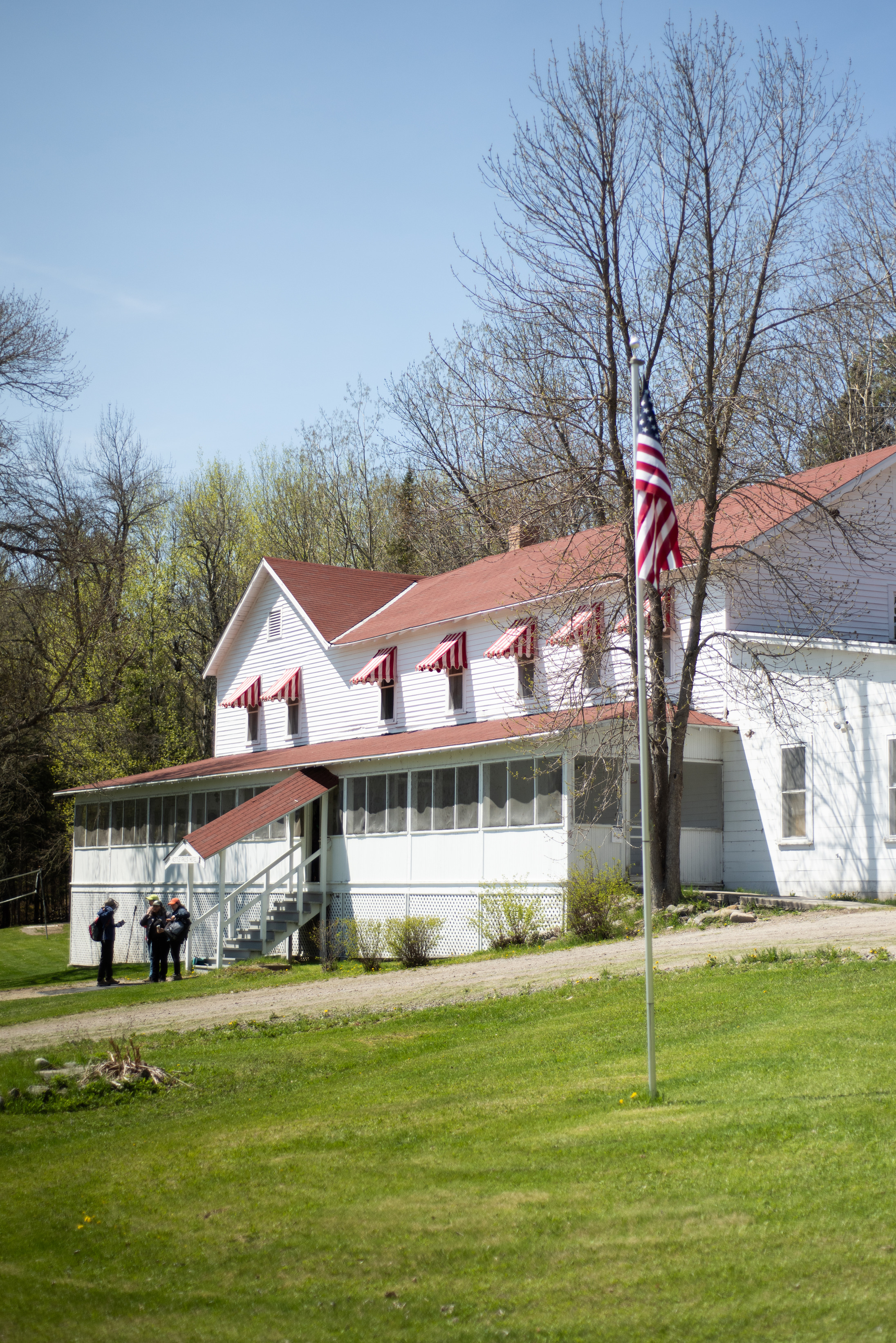 Photograph of the front entrance of Ketle Falls Hotel with a red roof, red-and-white striped awnings, and a screened-in porch.