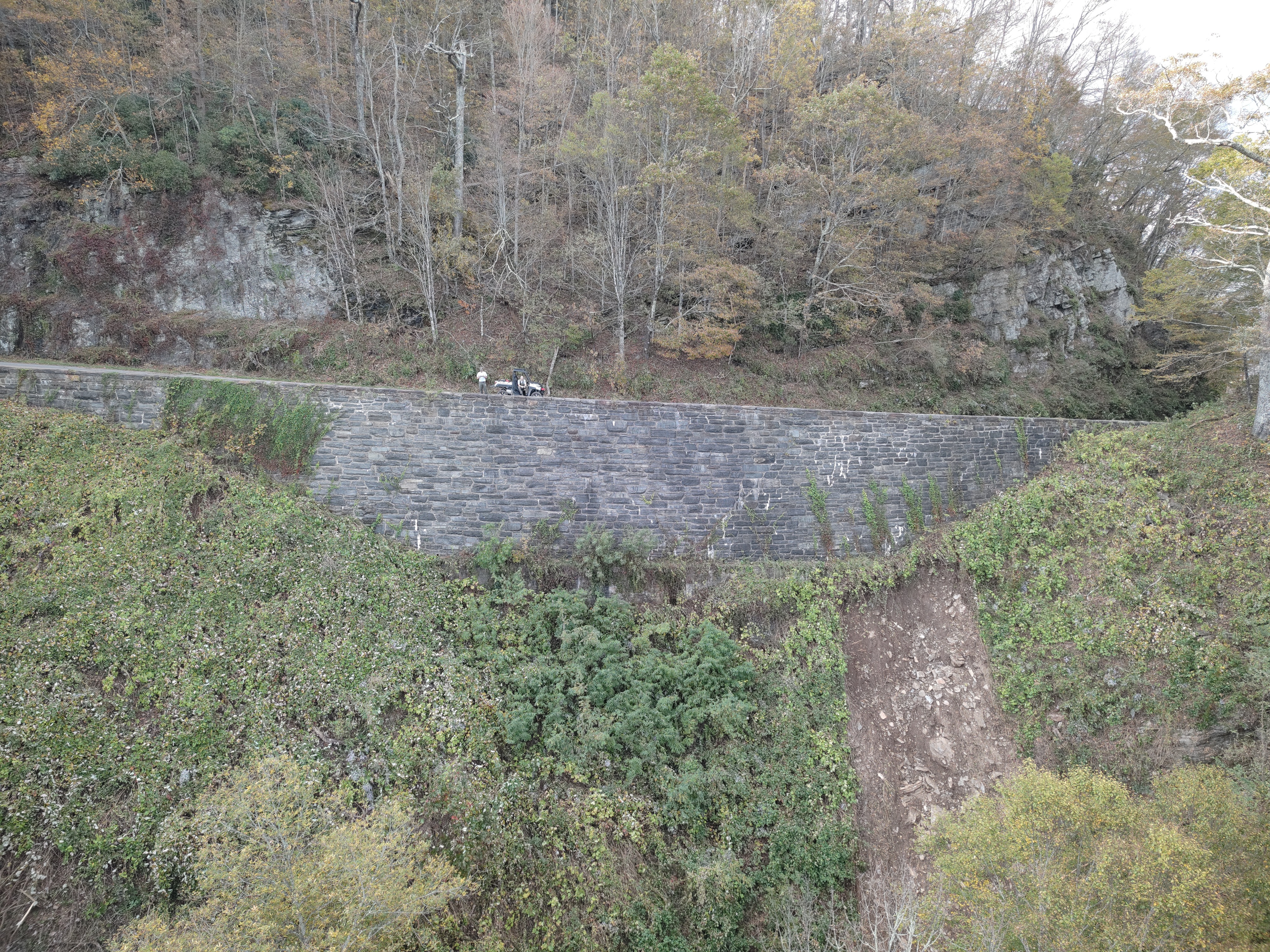 NPS crews survey slide damage below a retaining wall at milepost 319 on the Parkway caused by Hurricane Helene. 