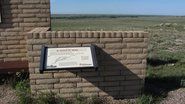 A brick wall with a wayside in front of it.