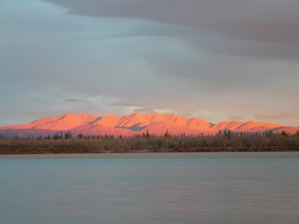 a river, with distant mountains tinged pink by sunlight