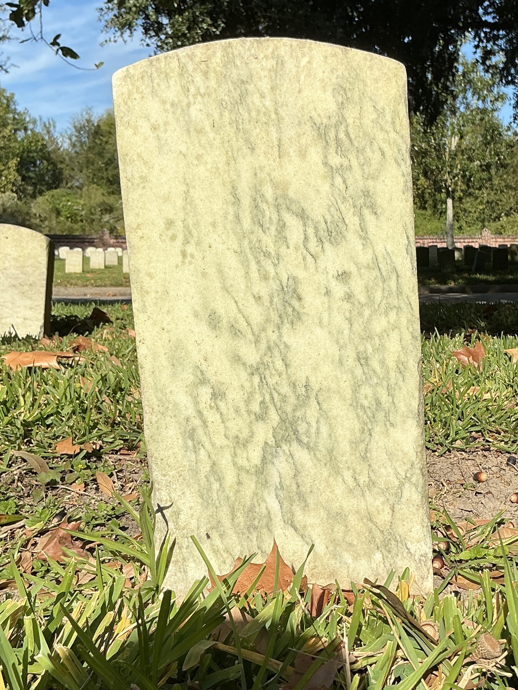 Back of historic upright marble headstone with recessed shield face.