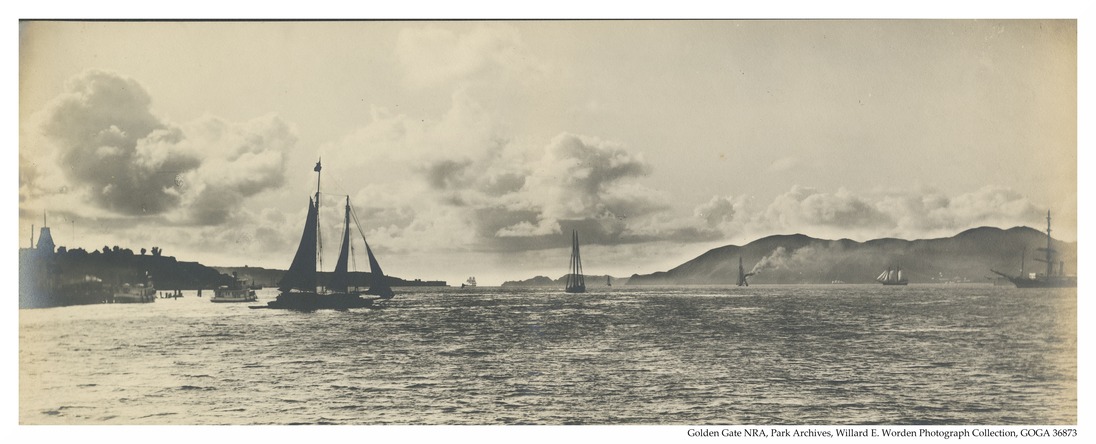 picture of the Golden Gate Strait prior to the golden gate bridge. there are many ships and ferries in the foreground and the Marin Headlands in the background. 