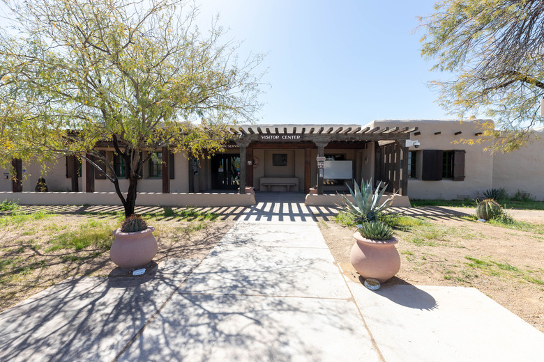 A single story building with a sign that reads, Visitor Center. A paved walkway leads to the front door. 