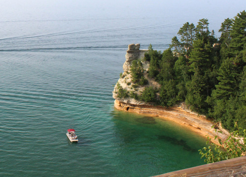 Pontoon boat in Lake Superior near a cliff face