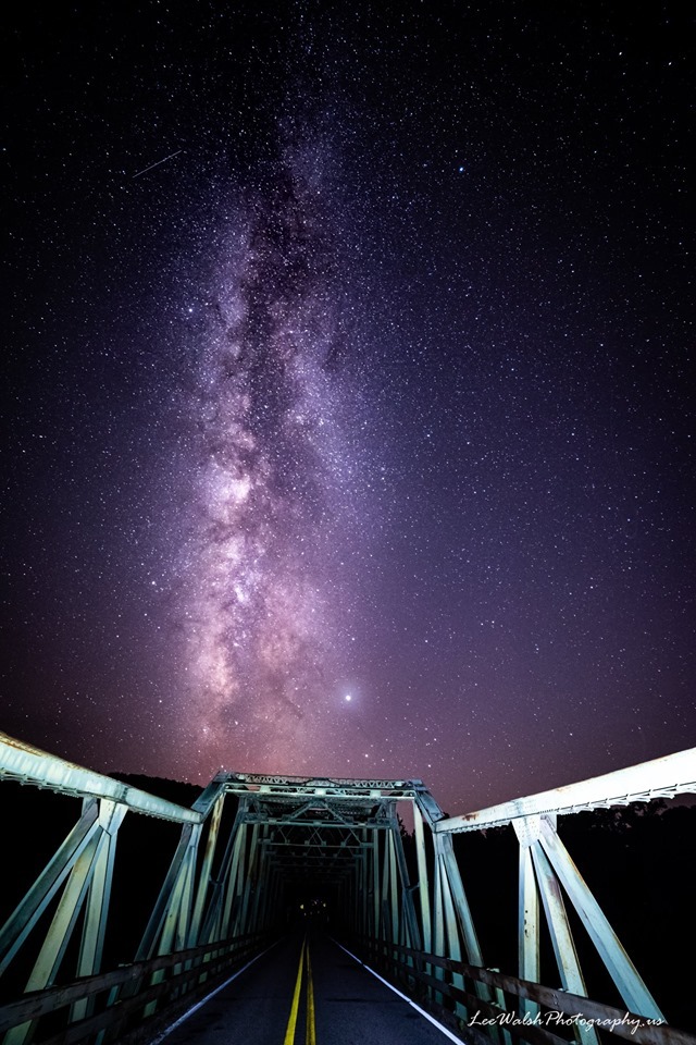 A cluster of stars above a steel truss bridge