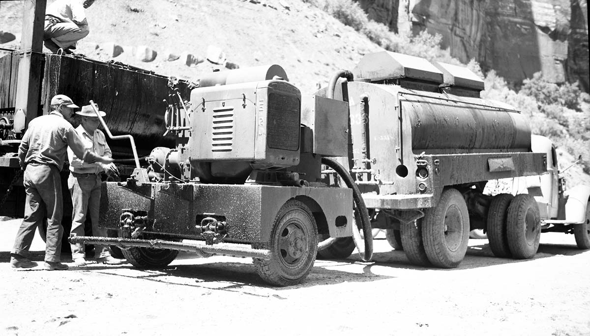 Three men operating 1500-gallon tanker and road oil distributor at work on sealing Route 2. Tanker and distributor (fog-sprayer) obtained from war.