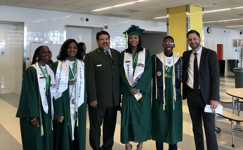 Six people stand in a line smiling and posing for a group photo
