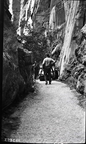 Narrows Trail construction with rolling finished, four workers take a break at a rock cut.