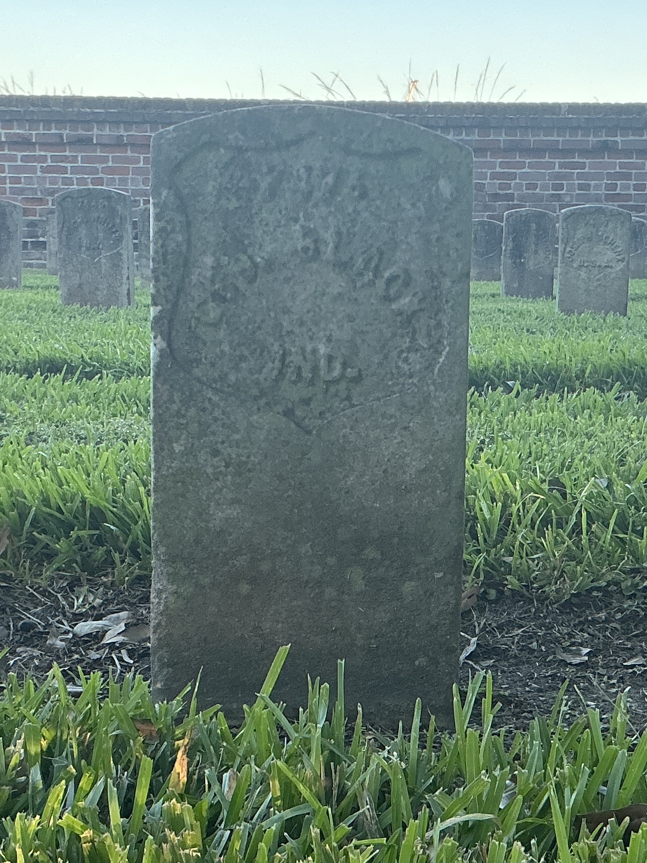 Front of historic upright marble headstone with recessed shield face.