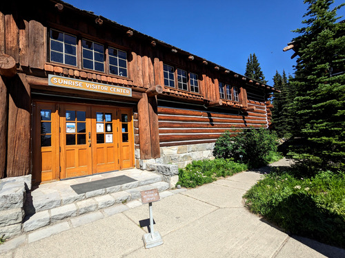 Several stone stairs lead to honey-colored double doors on a large log cabin-style building