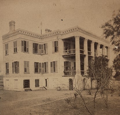 Black and white photograph of a Union Hospital in South Carolina. A white three story building with lots of windows and a porch with columns in the front façade. Small trees are in the forefront.