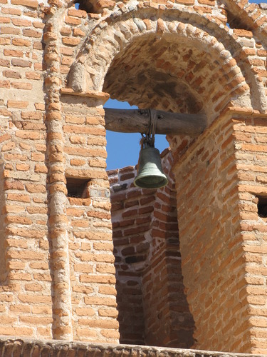 burnt brick with mortar and copper bell hanging from post