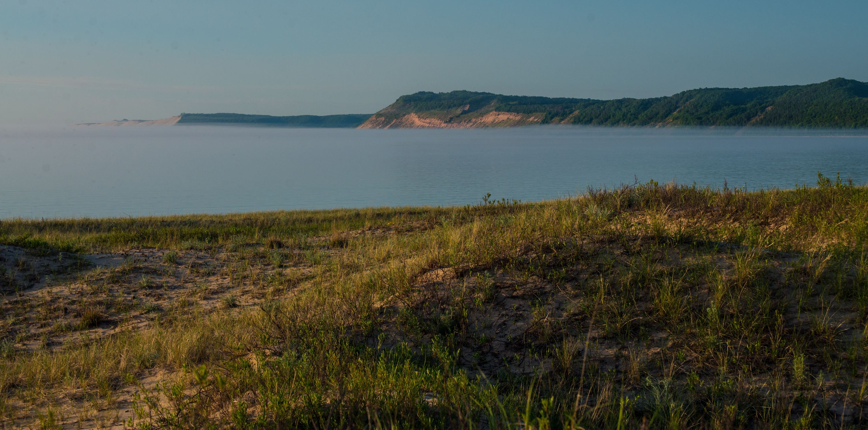 Sand dunes in the distance against a large lake