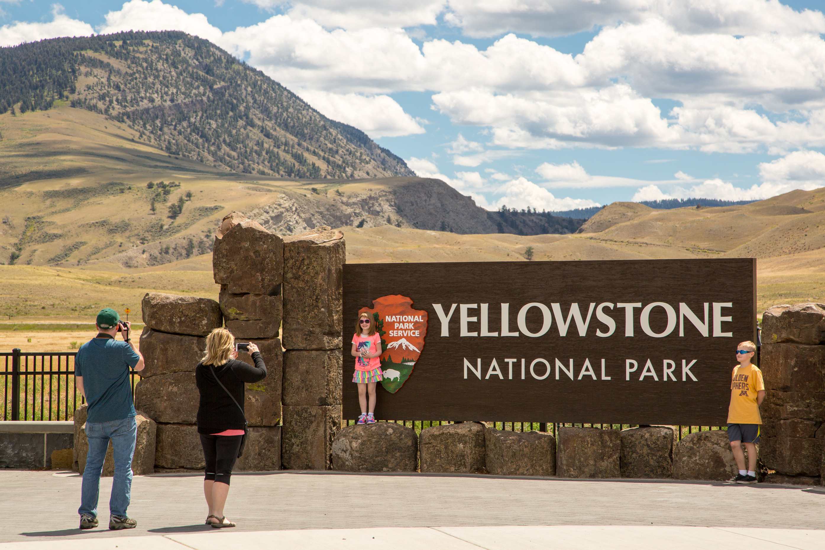 Family posing for pictures in front of the Yellowstone National Park sign