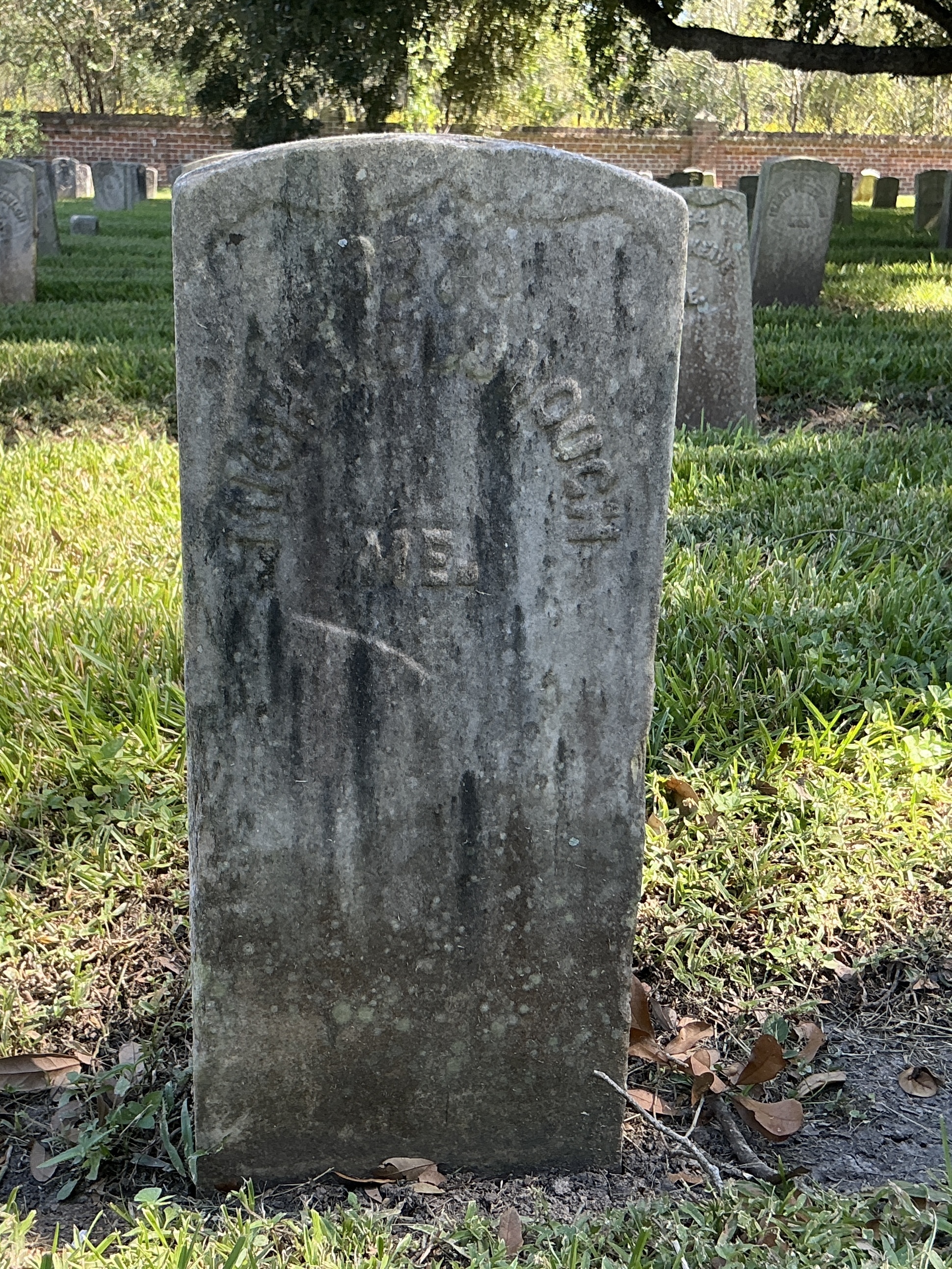 Front of historic upright marble headstone with recessed shield with recessed lettering face.