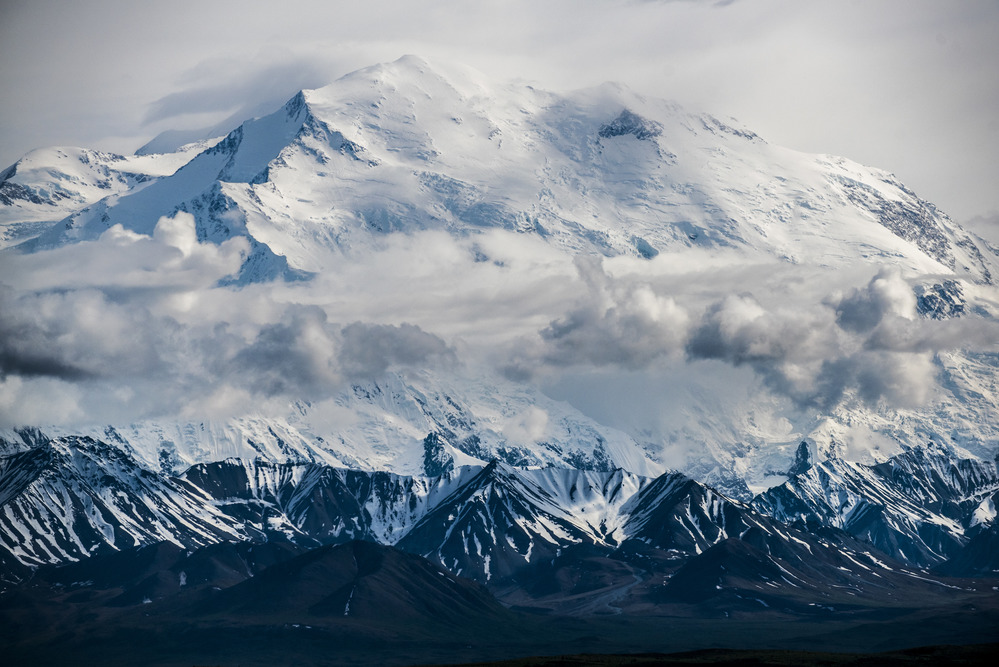 A landscape of hills, forests and a huge, snowy mountain