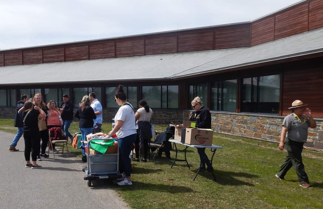 A group of people standing along a trail and sharing outdoor toys with passerby. 