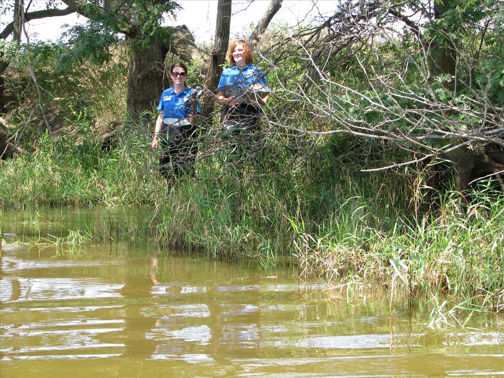 Two SCA interns stand along the edge of the pond.