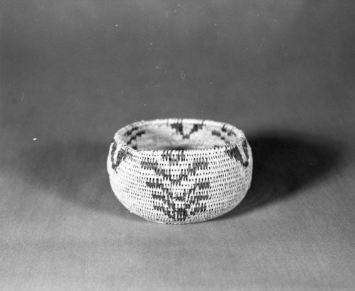 Private Collection. Object: Miwok basket. Dimensions: 4 1/2 x 2-3/4". Materials: Redbud, bracken fern, split shoot probably redbud. Technology: Single rod clockspring start fag ends trimmed on work face, moving ends trimmed on interior interlocking stitching. Design continues to top coil. Collection History: Calaveras County, California. Possibly from the Arollas family, Angels Camp area. Photographed by Michael Dixon. Catalogued by Craig Bates and Barbara Beroza. Yosemite Collections, National Park Service.