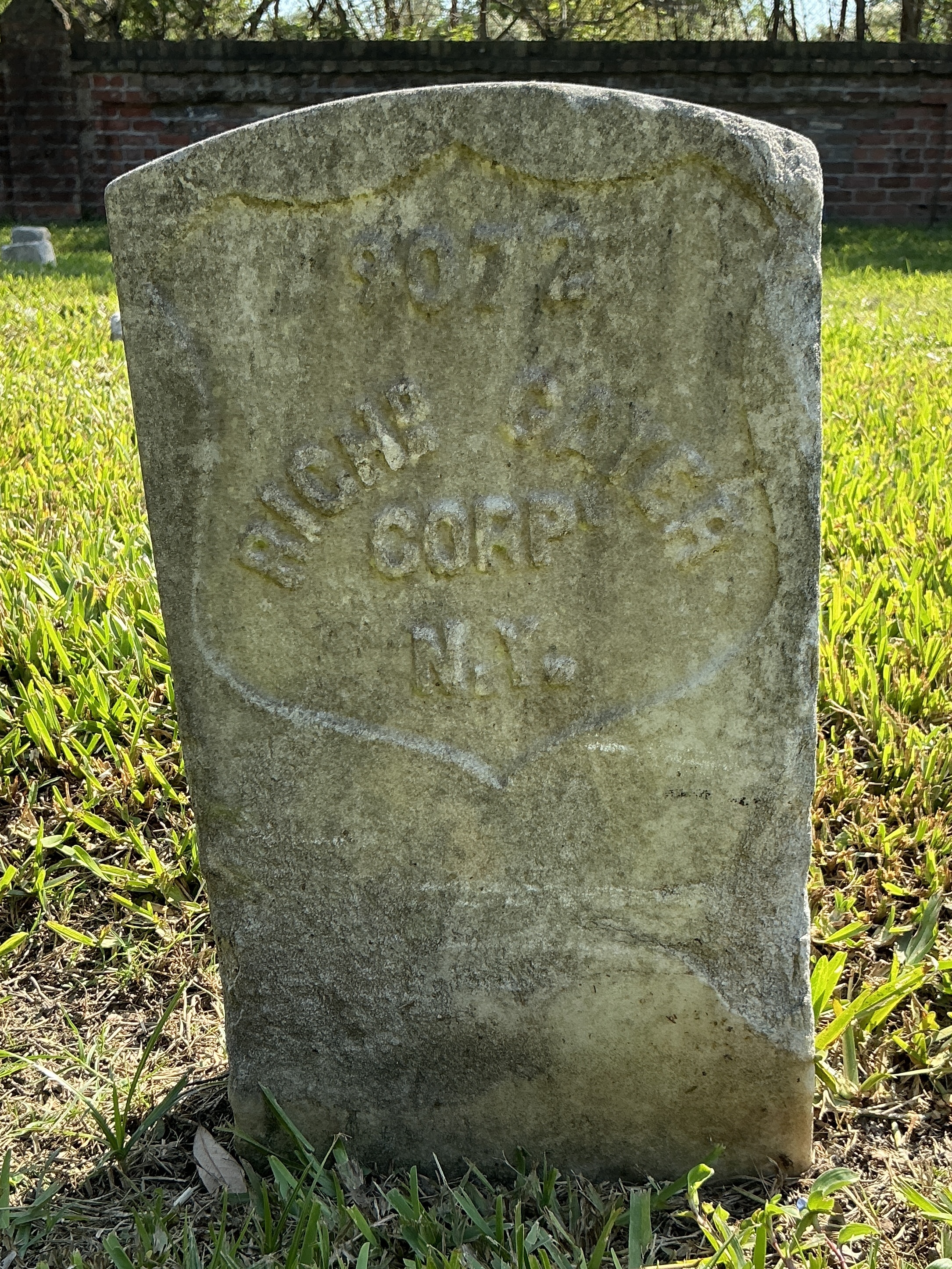 Front of historic upright marble headstone with recessed shield face.