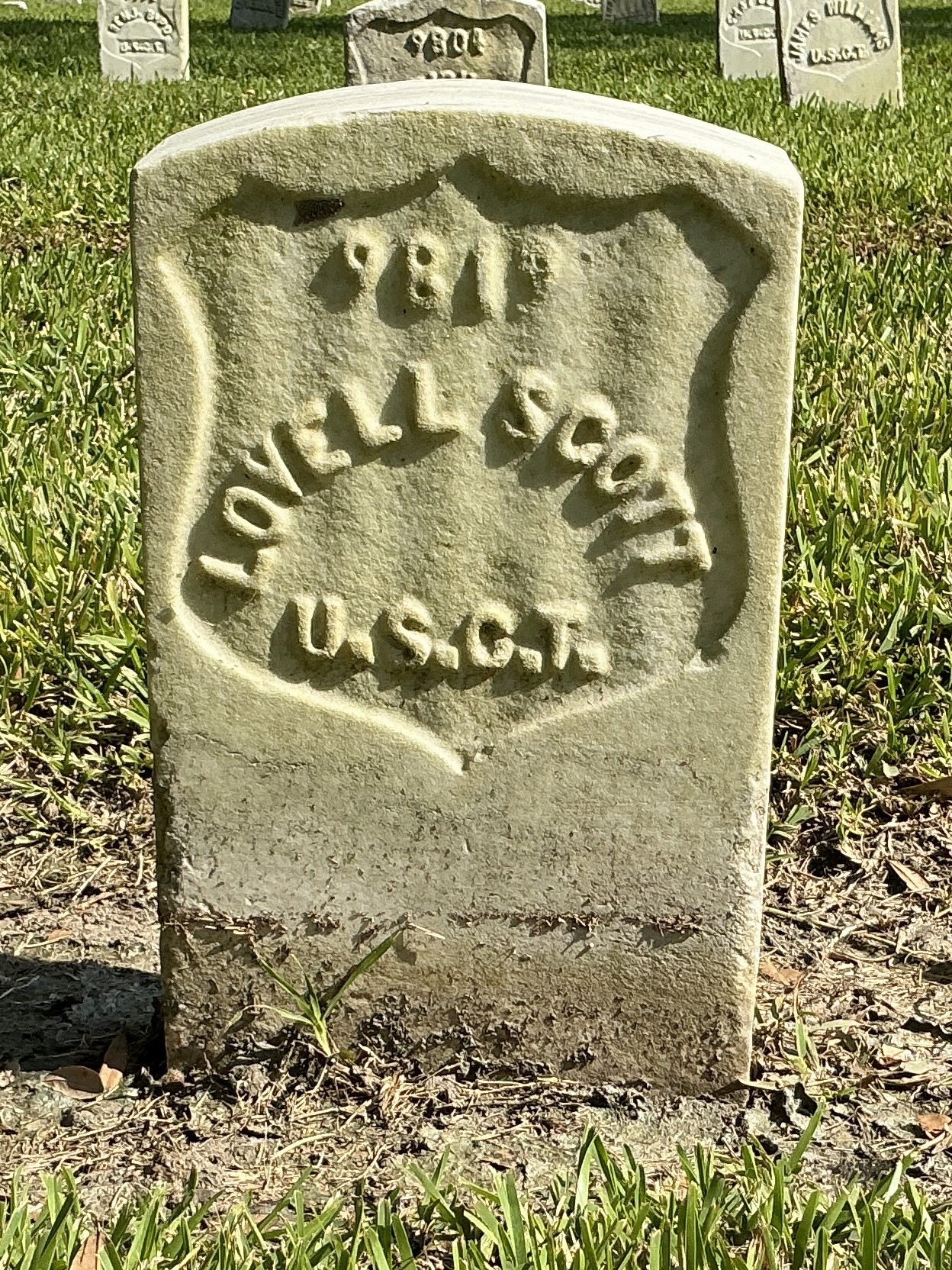 Front of historic upright marble headstone with recessed shield face.