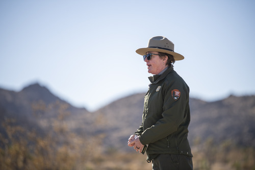 Park Superintendent Jane Rodgers in green and grey NPS uniform, speaking at the groundbreaking ceremony with desert landscape in background.