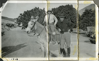 This is an historic black and white photograph from the Scotty's Castle Historic Photograph Collection, Death Valley National Park of Carrie Lee Johnson riding a burro while Albert M. Johnson leans against haunch. Photograph is  out of focus. Circa 1928. Photographed by Mat Roy Thompson.